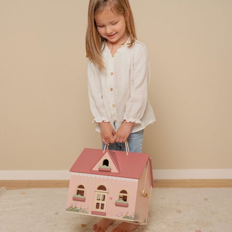 bimba che tiene in mano per la maniglia la casa delle bambole rosa
