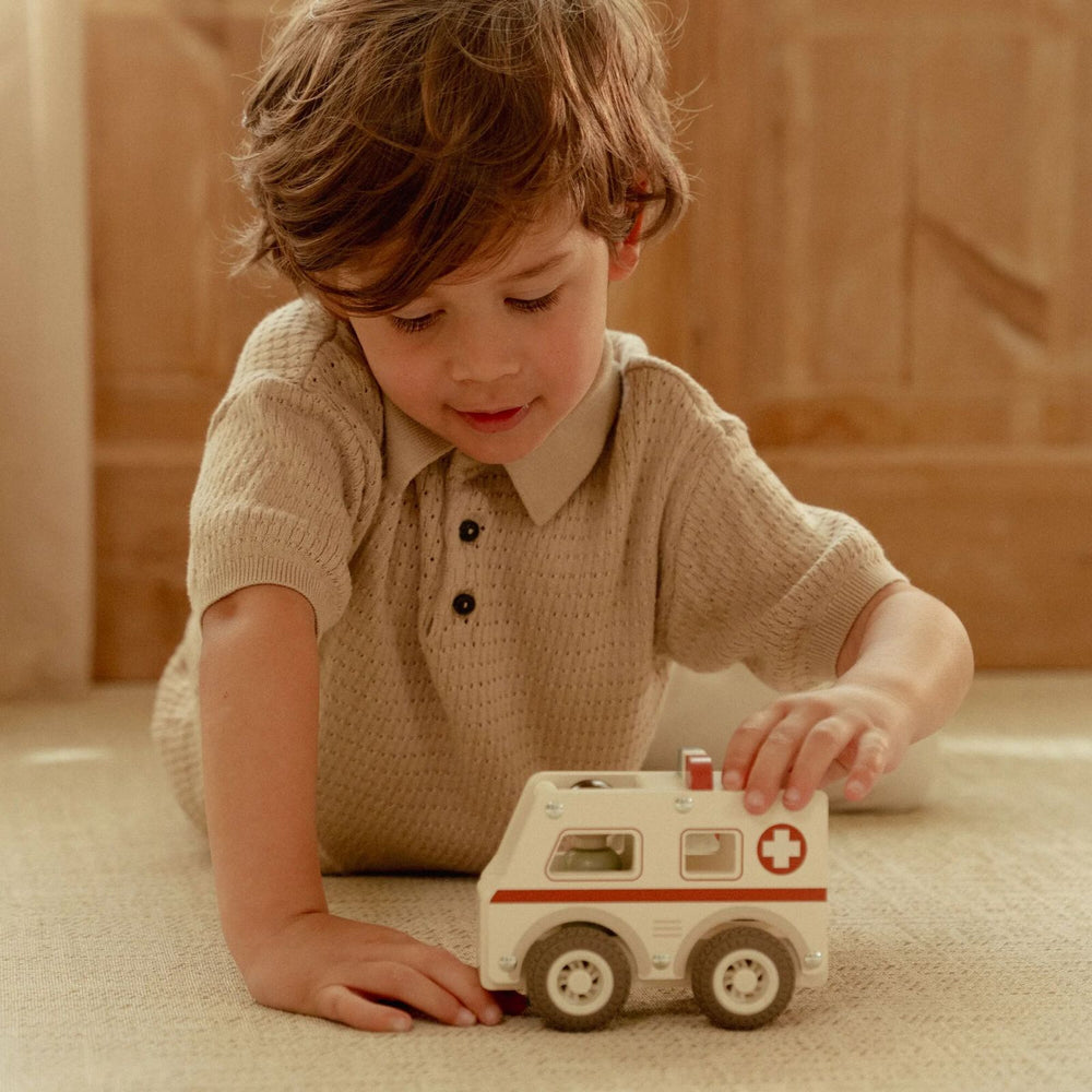bimbo che gioca con ambulanza in legno
