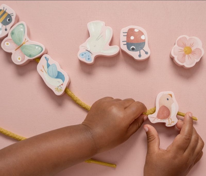 Lacing Beads, formine da infilare, Little Dutch. In foto bambina che gioca con le formine a tema Fiori e Farfalle