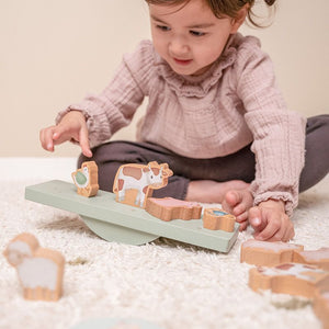 bimba che gioca con balance e animali sul tappeto