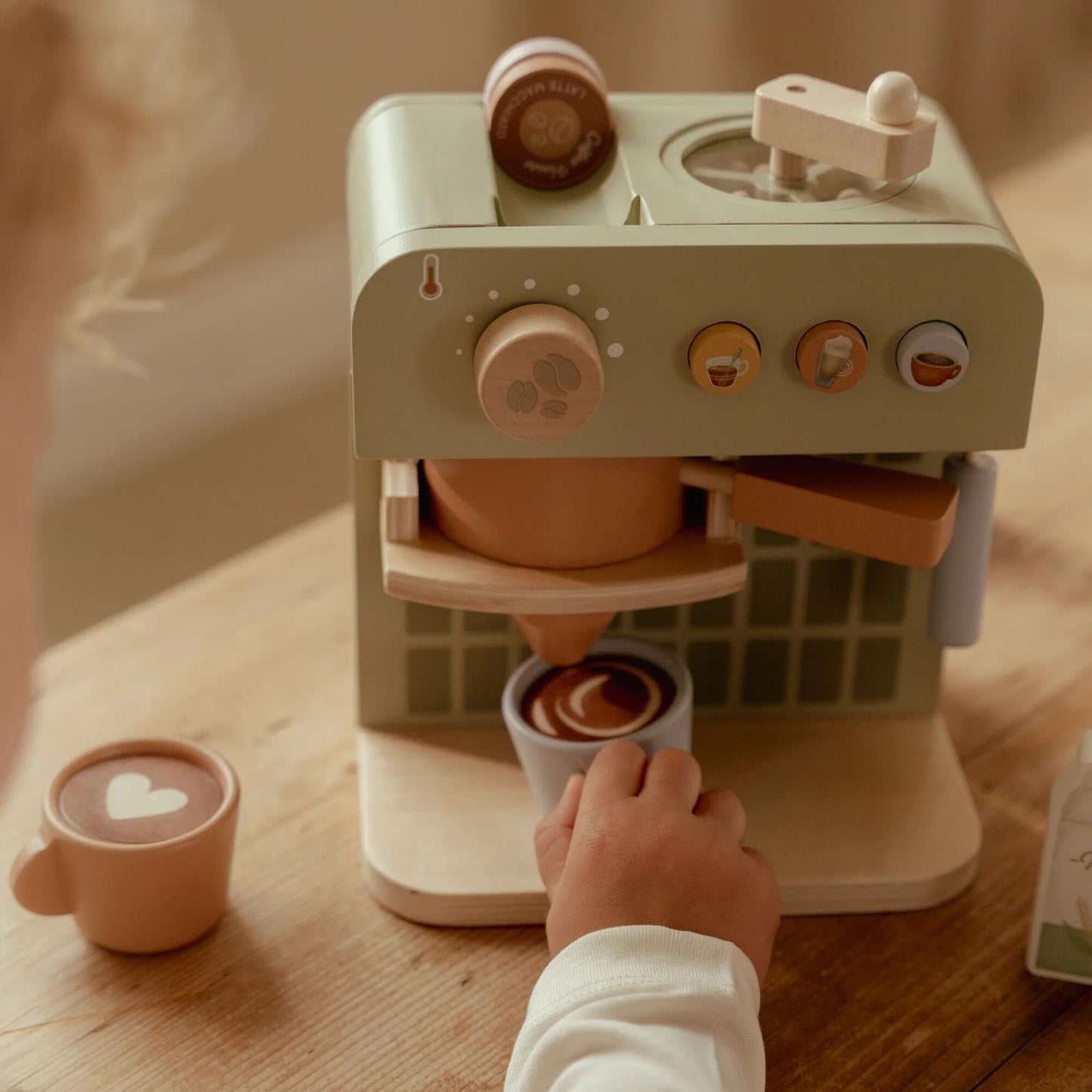 Bimbo che gioca con coffee maker tenendo una tazza in mano