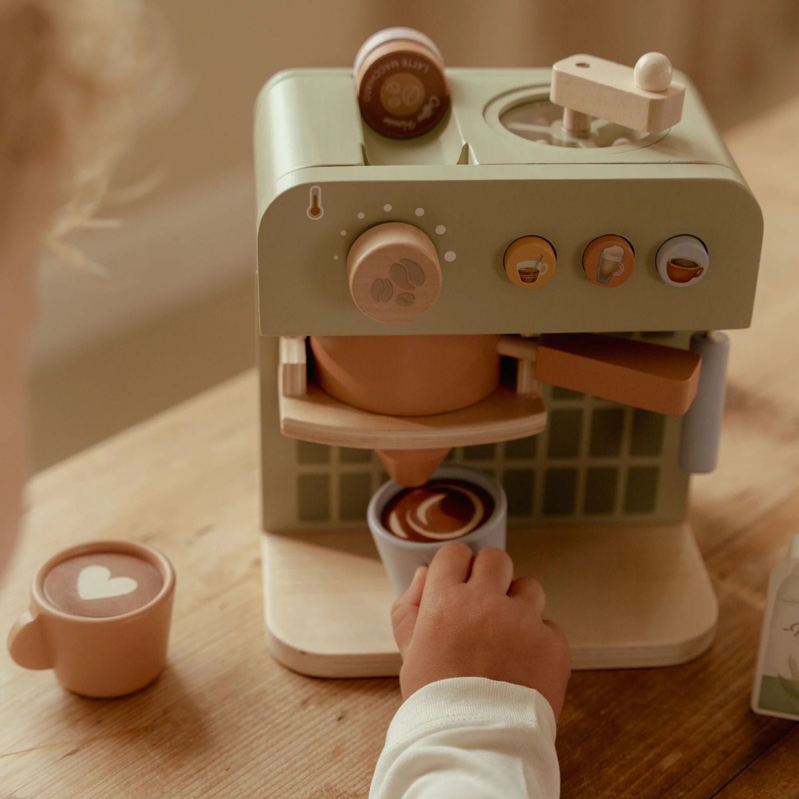 Bimbo che gioca con coffee maker tenendo una tazza in mano