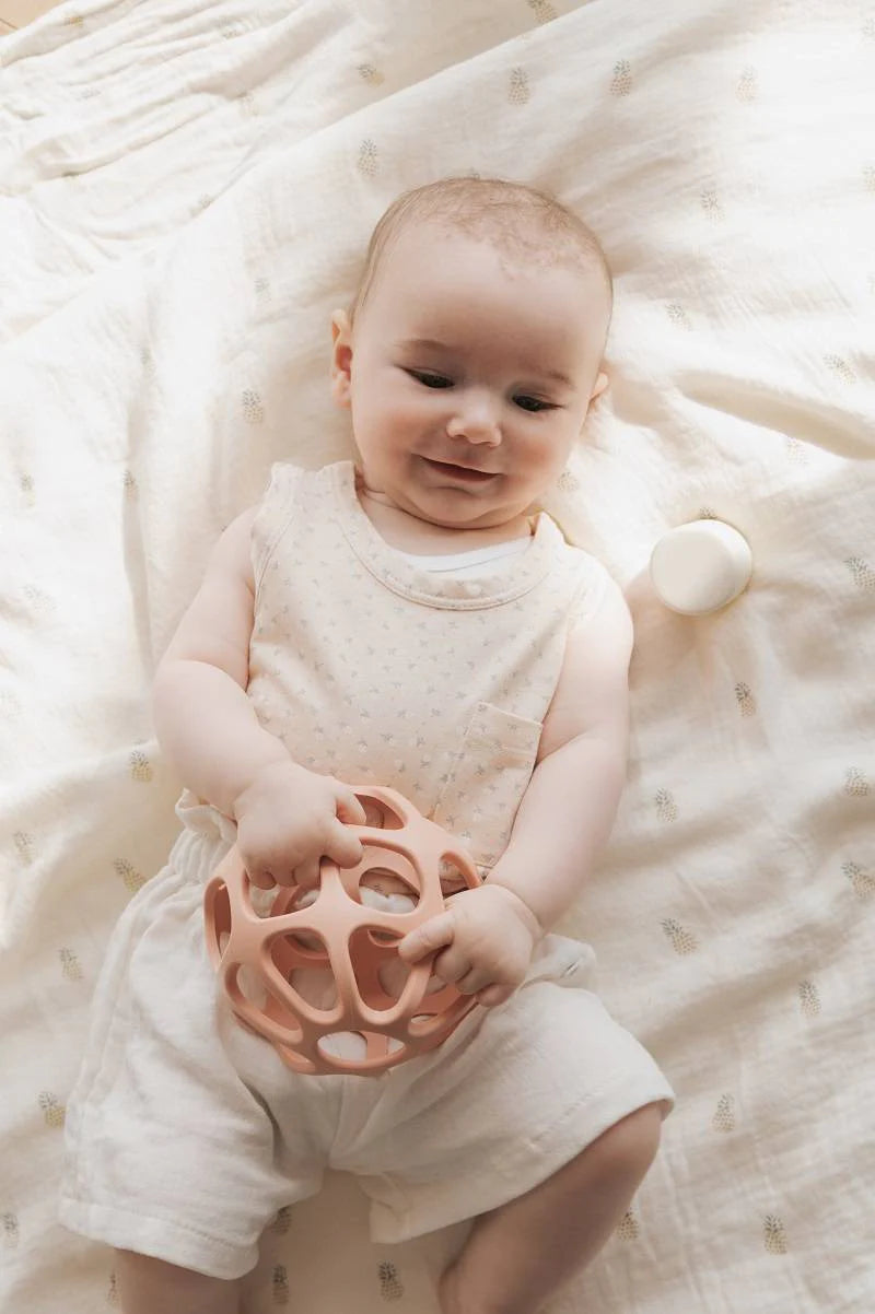 Massasggiagengive a pallina in silicone, Bamboom. In foto bambina coricata che gioca con il dentaruolo rosa