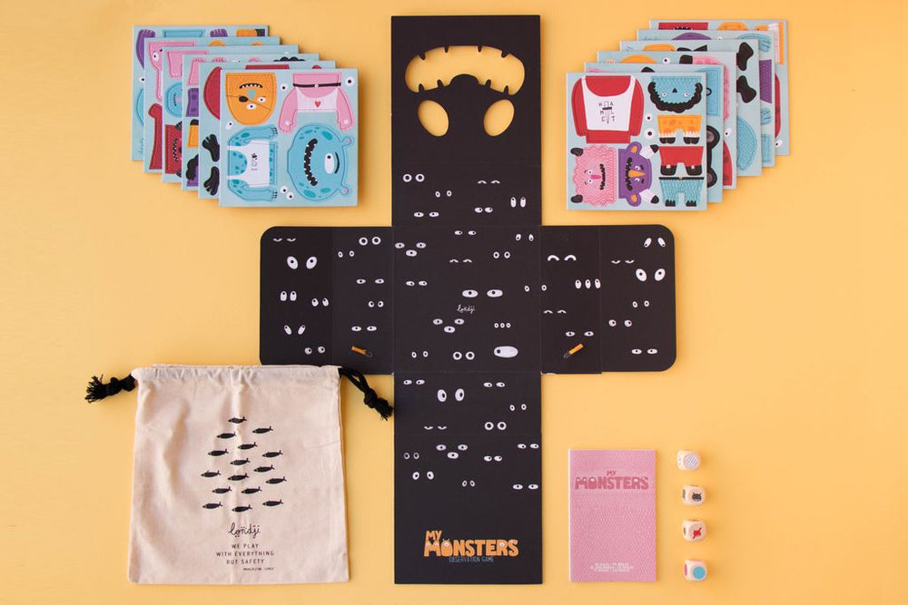 Interno della scatola e relativo contenuto: 60 pezzi di cartone per costruire i mostri, 4 dadi, sacchetto di stoffa per contenere tutti  pezzi e libretto istruzioni