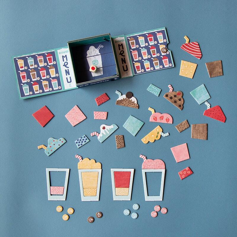 Interno della scatola e relativo contenuto: schede gioco a forma di bicchiere e ingredienti dei frullati in cartone riciclato