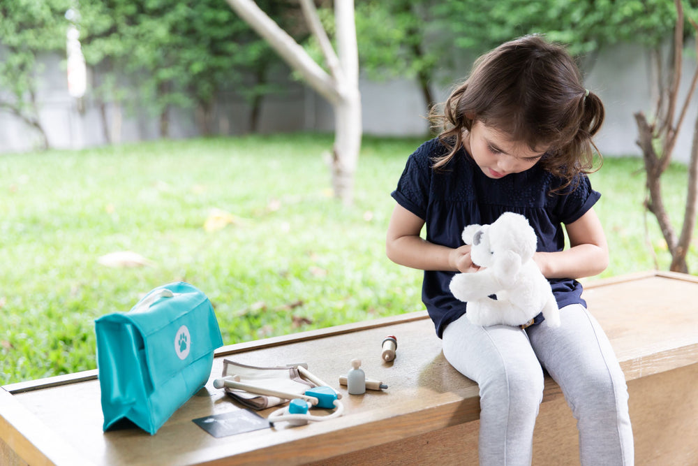 Set gioco Veterinario, Plan Toys. Bambina che gioca con il set curando una pecora peluche