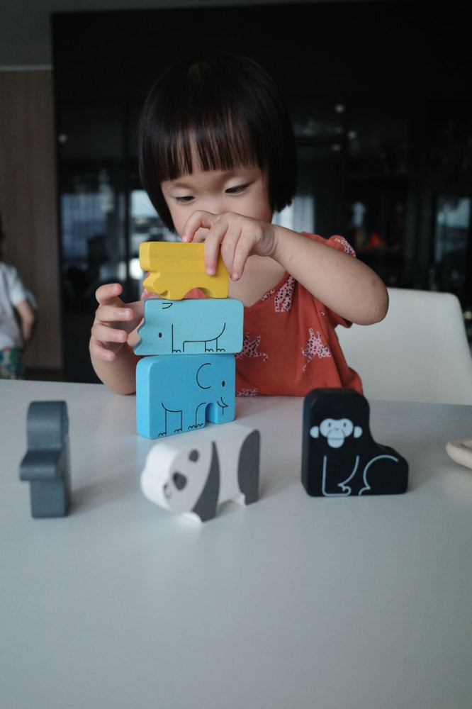 Gioco Puzzle a tema animali in legno, "Animal Puzzle Game", Plan Toys. Bambina che costruisce una torre impilando uno sopra l'altro gli animali.