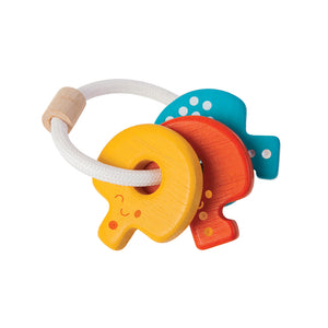 Sonaglio portachiavi in legno, "Key Rattle", Plan Toys. Sonaglio composto da 3 chiavi dai colori accesi: giallo, rosso e blu, tenuti insieme da un anello in corda bianco.