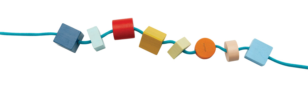 Geo Lacing Beads, perline geometriche colorate da infilare in legno, Plan Toys. Set di 15 perline di 3 forme geometriche diverse da infilare in una corda azzurra.