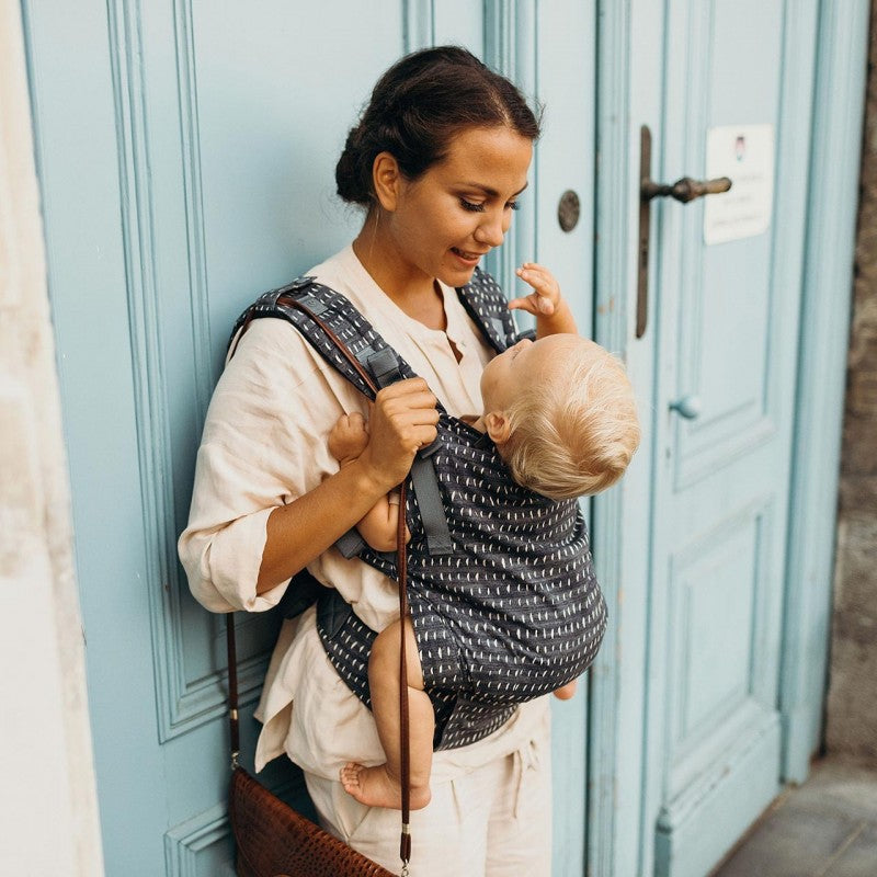 mamma che porta nel marsupio un bambino e lo guarda