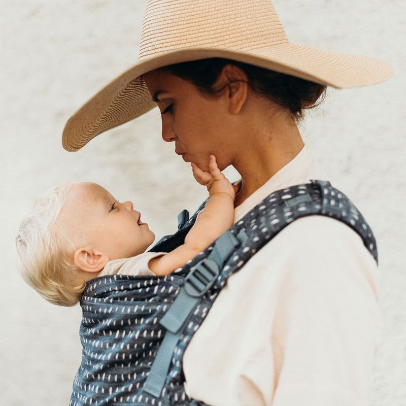 mamma con cappello in paglia e bimbo nel marsupio