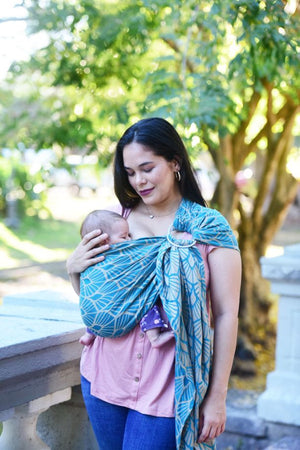 Fascia ad anelli Portabebè, Neko Slings, Modello KIDONYA MARINA. Fascia ad anelli azzurra con pattern a conchiglia. Madre che porta il bambino nella posizione davanti cuore a cuore
