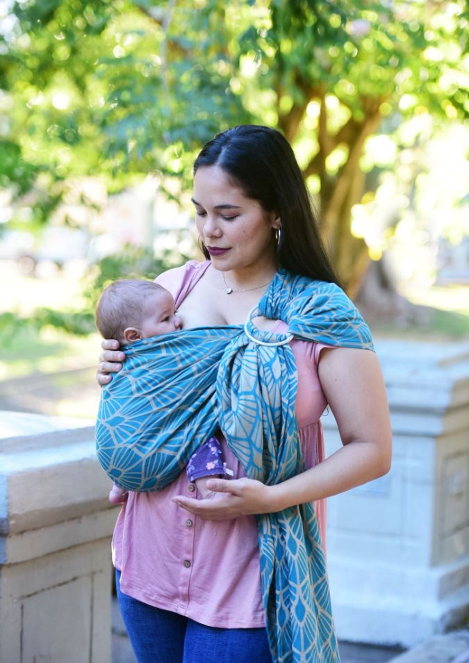 Fascia ad anelli Portabebè, Neko Slings, Modello KIDONYA MARINA. Fascia ad anelli azzurra con pattern a conchiglia. Madre che porta il bambino nella posizione davanti cuore a cuore