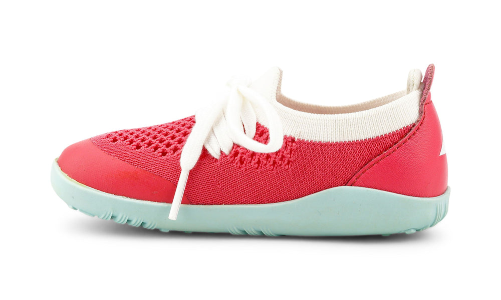 I-Walk Play Knit Guava/White, Bobux. Vista laterale della scarpina con parte centrale in tessuto traforato rosso, laccetti bianchi, punta e tallone in sintetico rosso, suola gommata azzurra.