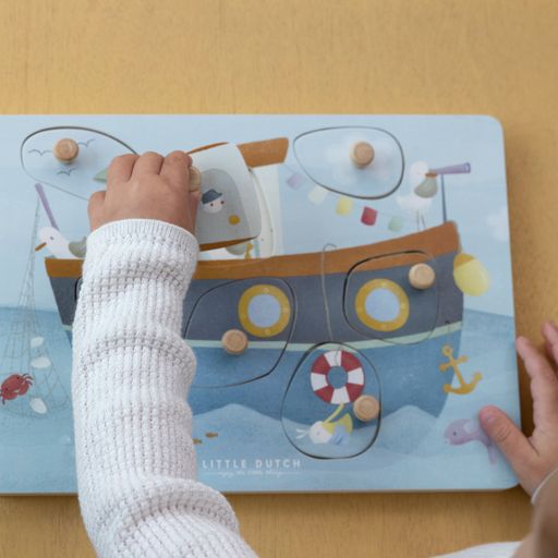 Sound Puzzle Sailor Bay, puzzle sonoro in legno, Little Dutch. Bambino che gioca con il puzzle. I sensori risponderanno quando si solleva un pezzo di puzzle e si rivela l'illustrazione sottostante
