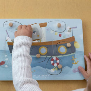 Sound Puzzle Sailor Bay, puzzle sonoro in legno, Little Dutch. Bambino che gioca con il puzzle. I sensori risponderanno quando si solleva un pezzo di puzzle e si rivela l'illustrazione sottostante