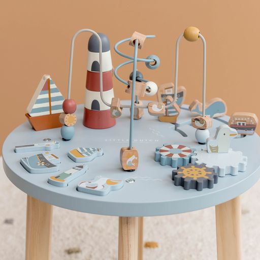 Activity Table, tavolino multiattività in legno, Little Dutch. Tavolino a tema Baia dei Marinai con elementi che richiamano il mare e la pesca. Il tavolino è azzurro con gambe color marrone chiaro. Il gioco impilabile rappresenta un faro, gli ingranaggi richiamano un timone, un salvagente e un gabbiano.
