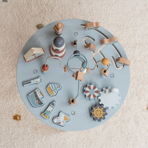 Activity Table, tavolino multiattività in legno, Little Dutch. Tavolino a tema Baia dei Marinai con elementi che richiamano il mare e la pesca. Il tavolino è azzurro con gambe color marrone chiaro. Il gioco impilabile rappresenta un faro, gli ingranaggi richiamano un timone, un salvagente e un gabbiano. Vista del tavolino dall'alto