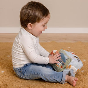 Cubo multiattività morbido multisensoriale a tema Baia dei Marinai, Little Dutch. Vista di un bambino seduto sul tappeto che gioca con il cubo.