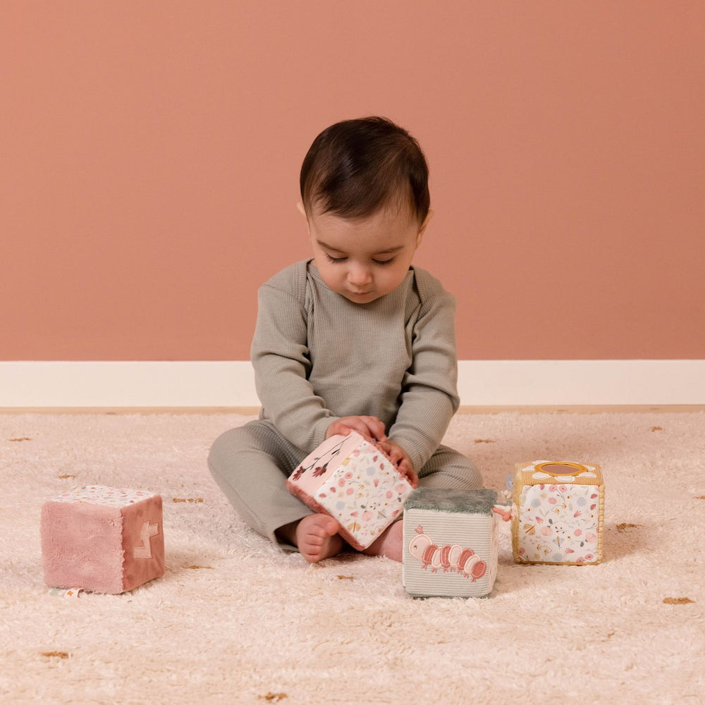 Soft Cubes Set, Set di cubi morbidi a tema Fiori e Farfalle, Little Dutch. Bambino seduto sul tappeto che gioca con i cubi.