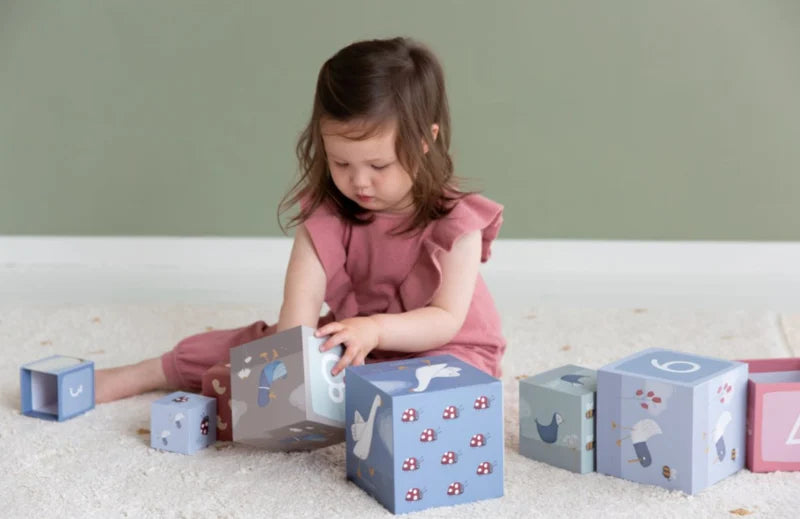 Blocchi impilabili in cartone a tema Little Goose, Little Dutch. Bambina seduta sul tappeto che gioca con un blocco