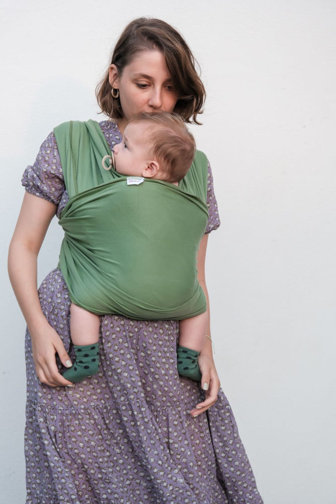 mamma che porta davanti bambino in fascia elastica verde